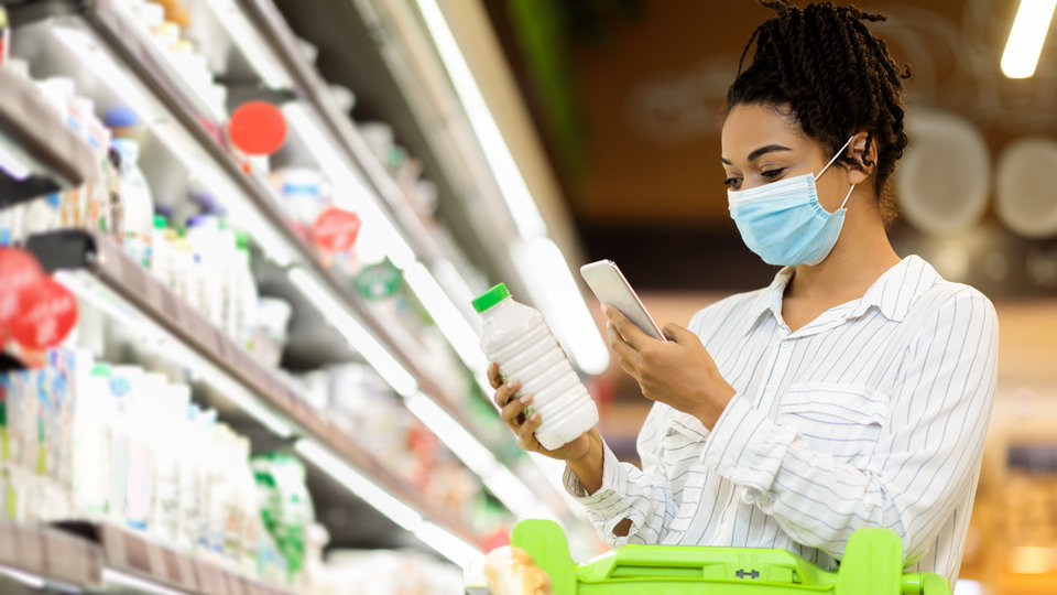 woman with mask shopping in dairy section of retail grocery store