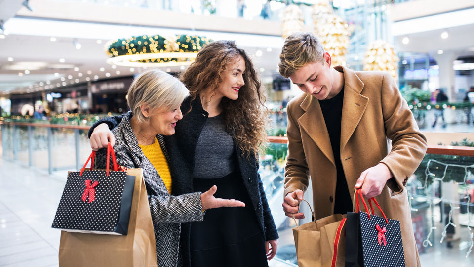 male and female shoppers with older woman reviewing purchases in retail shopping mall