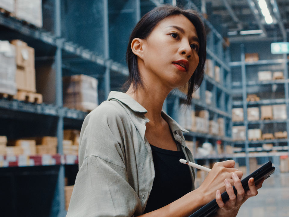 Femme dans un magasin utilisant un système de gestion des stocks à l’aide d’un stylet sur une tablette