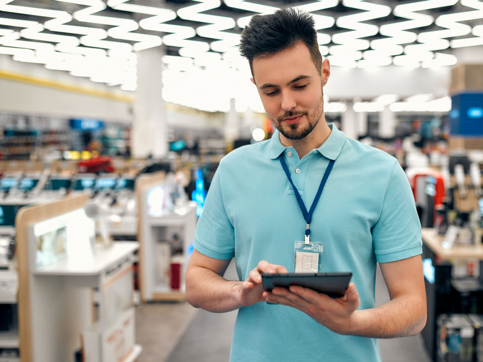 dipendente maschio nel retail analizza i dati di prevenzione taccheggio da un tablet elettronico nella corsia del negozio